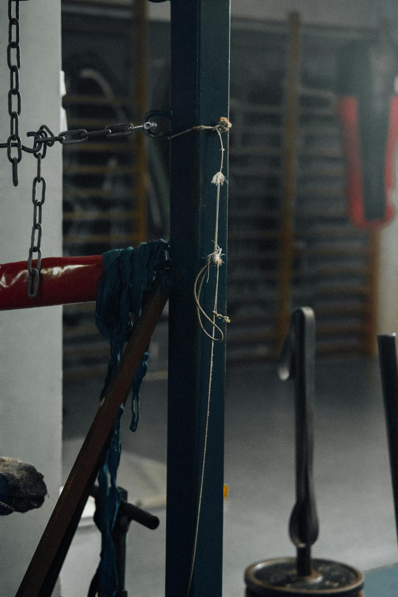 Close-up of boxing gym equipment with ropes and chains, creating a moody atmosphere.